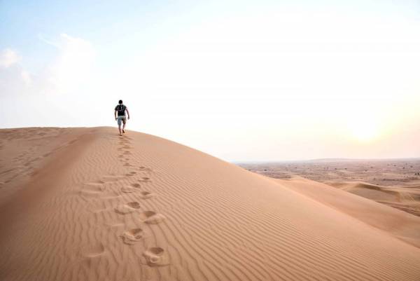 Man Walking Up Sand Dunes 
